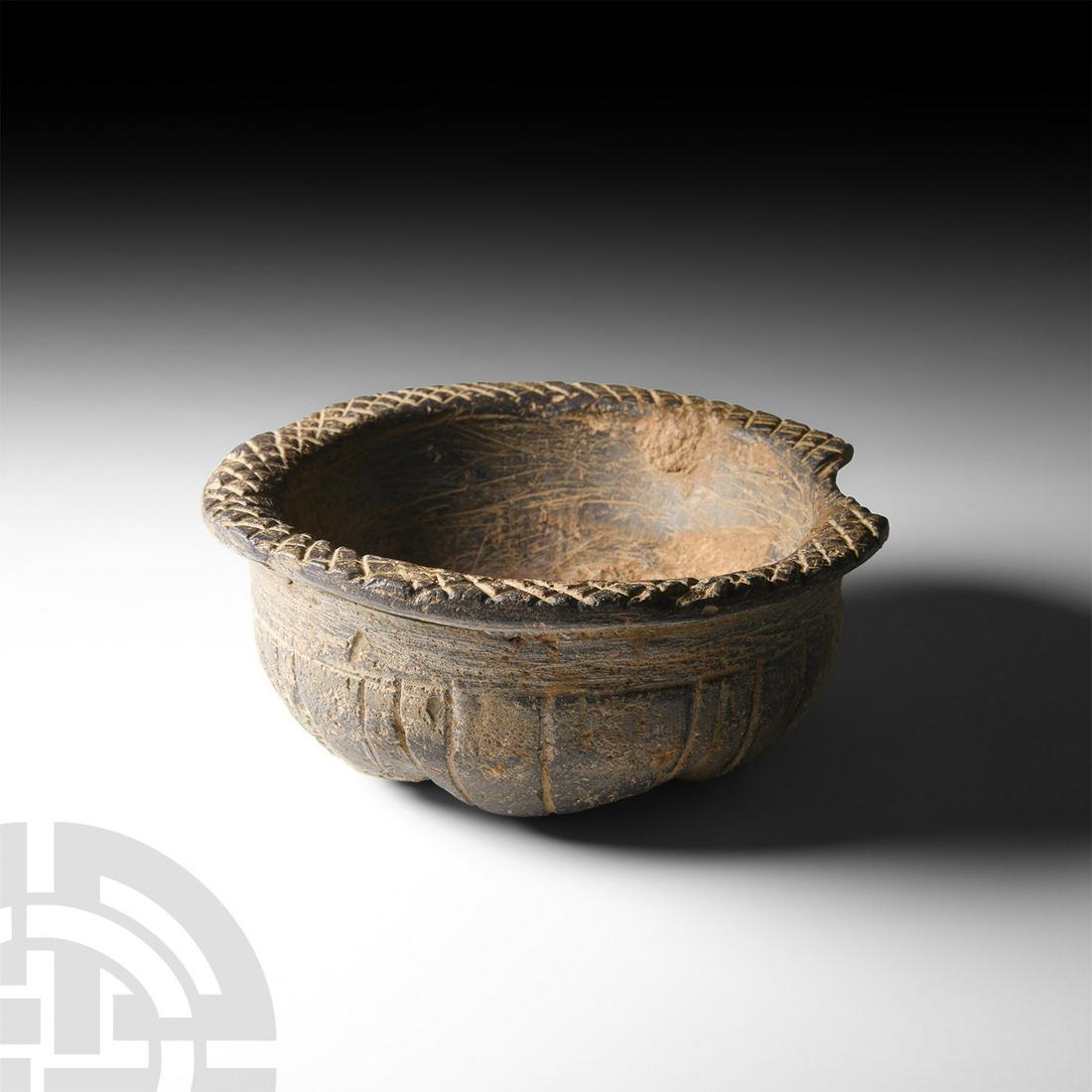Bactrian Engraved Vessel: 2nd millennium B.C. A shallow bowl with squat body tapering to a base composed of six grooved lobes or segments, flared rim with hatched engraving. 203 grams, 96 mm wide (3 3/4 in.) Acquired between 1