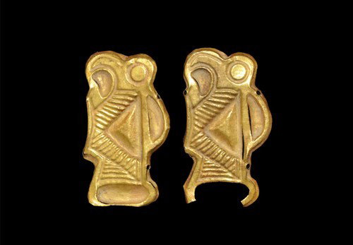 Merovingian Frankish Gold Zoomorphic Mounts: Circa 6th century AD. A pair of repoussé gold foil mounts in the form of stylized birds with discoid eye, hooked beak, D-shaped wing and ribbed detailing on the body and tail; the lip pierced in four