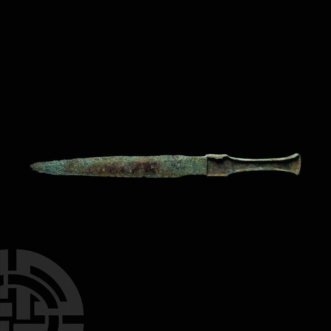 Luristan Handled Dirk: Circa 12th century B.C. A substantial bronze dirk with slender leaf-shaped blade, narrow neck; slender grip with flared finial, lateral flanges to each face to secure an organic insert. Cf. Khorasani,