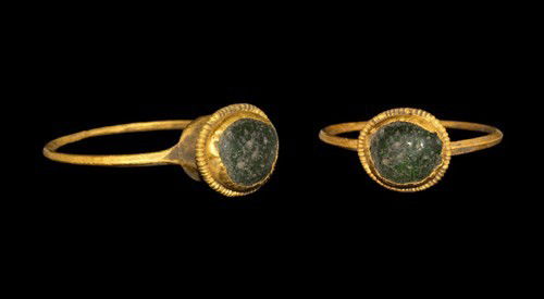 Roman Gold Intaglio Ring with Green Glass Cabochon: Circa 3rd century AD. A delicate gold ring comprising a triangular-section hoop and tall bezel formed as an elliptical cell with filigree circlet enclosing a green glass cabochon. Gold and glass, 2.49
