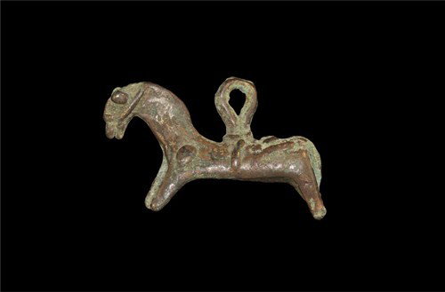 Near Eastern Luristan Bronze Horse Pendant: Circa 1200-800 BC. A cast bronze pendant in the form of a horse with bridle, saddle and girth; a thick suspension loop attached to the saddle; the underside of the figure hollow. Bronze, 31 grams, 54 