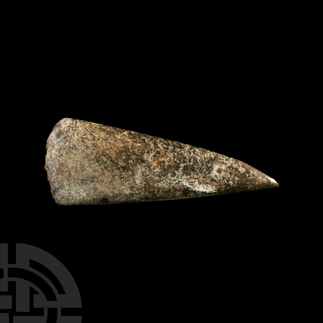 Stone Age Neolithic Polished Axehead: Circa 4th millennium B.C. A finely polished, slightly asymmetric axe with thin body tapering to a pointed butt with convex cutting edge in a mottled granite; possibly from northern Britain. Cf. Evans,