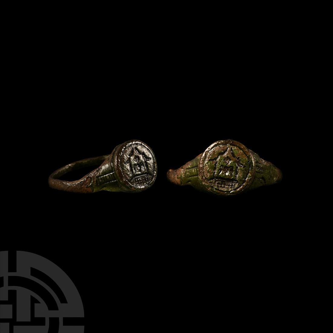 Medieval Ring with Building: 12th-14th century A.D. A copper-alloy ring composed of a slender hoop with shaped shoulders, the discoid bezel engraved with a single cell building with pitched roof, a winged figure or animal standin