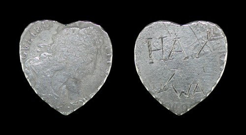 Engraved Love Token: Circa late 17th century. Formed from a shilling of William III, cut to a heart shape with deckled edges; the reverse of the coin smoothed and engraved with a broken arrow and initials HA above WA. 4.2