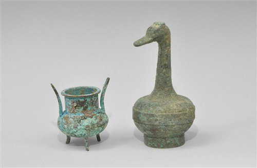 Near Eastern Bronze Vessel Group: Circa 19th century AD or later A mixed group of cast bronze vessels comprising: a miniature cauldron with three curved legs, thick rim and two prong handle; a small ewer with discopid body, tall basal