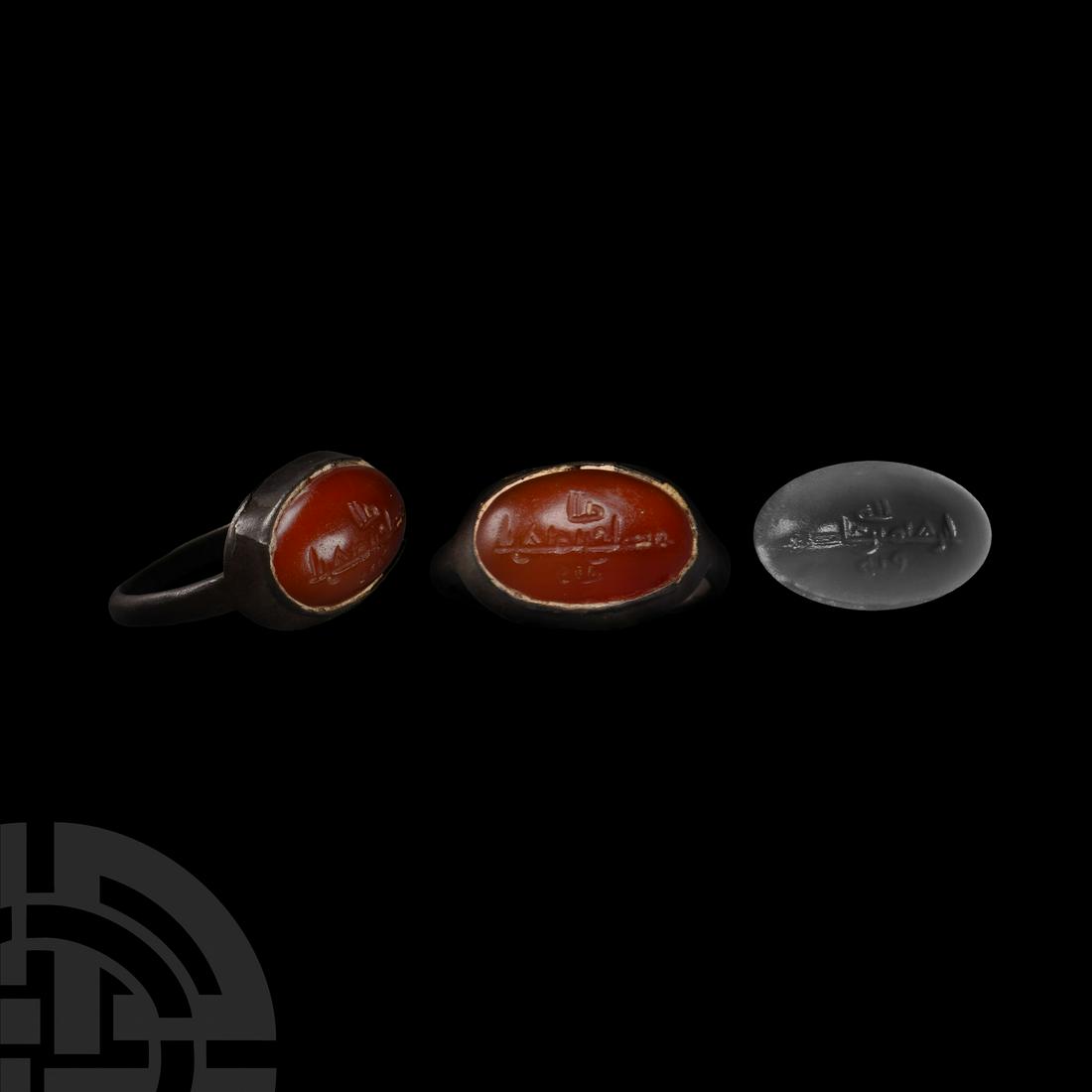 Medieval Period Silver Ring with Inscribed Gemstone: Circa 15th-16th century A.D. The hoop supporting an oval bezel set with carnelian(?) cabochon engraved over three lines with Islamic script. 4.21 grams, 26.15 mm overall, 18.27 mm internal diameter (a