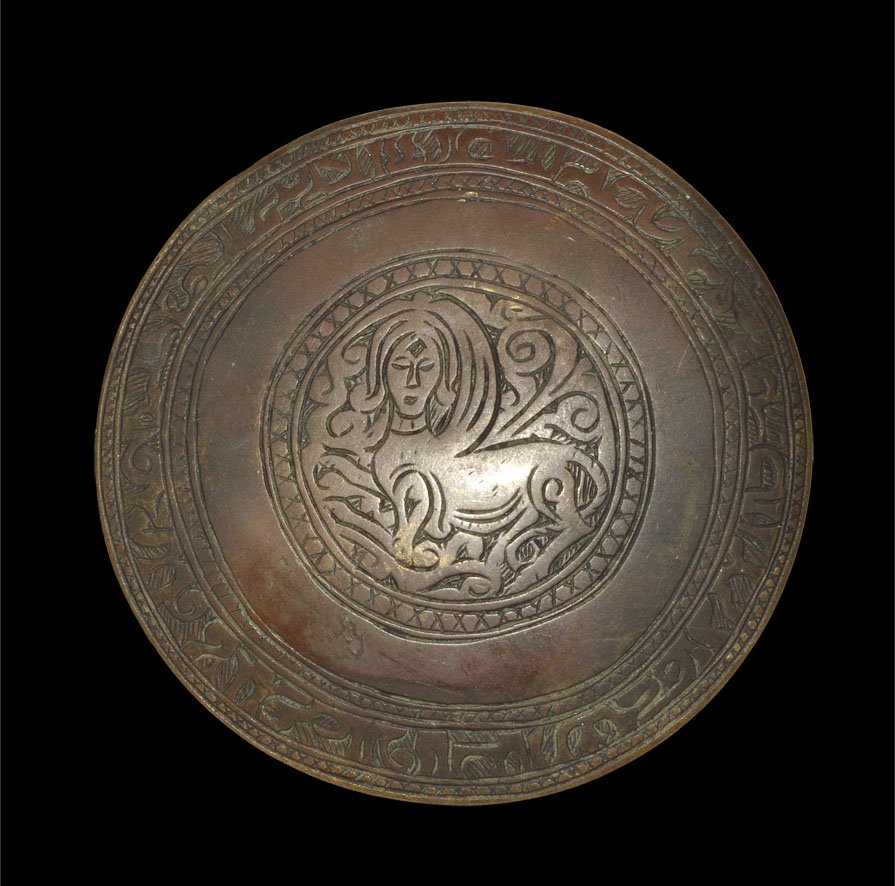 Islamic Bronze Engraved Disc Mount: Circa 17th-18th century AD. A substantial cast bronze disc mount with a band of calligraphic text to the border; the central motif a sphinx advancing on a field of vegetation within a hatched border; 
