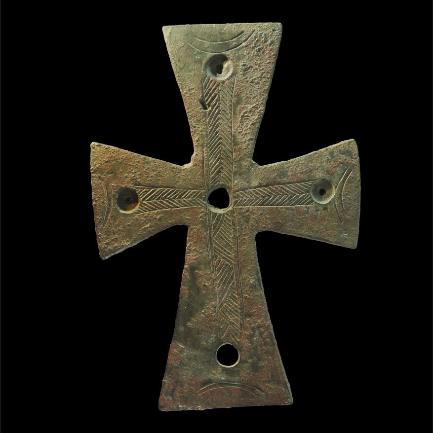 Byzantine Bronze Cross Mount: Circa 12th century AD. A cast bronze cruciform mount with four pierced recesses; the expanding-arm cross with bands of incised herringbone texturing; at the end of each arm an incised bilinear crescen