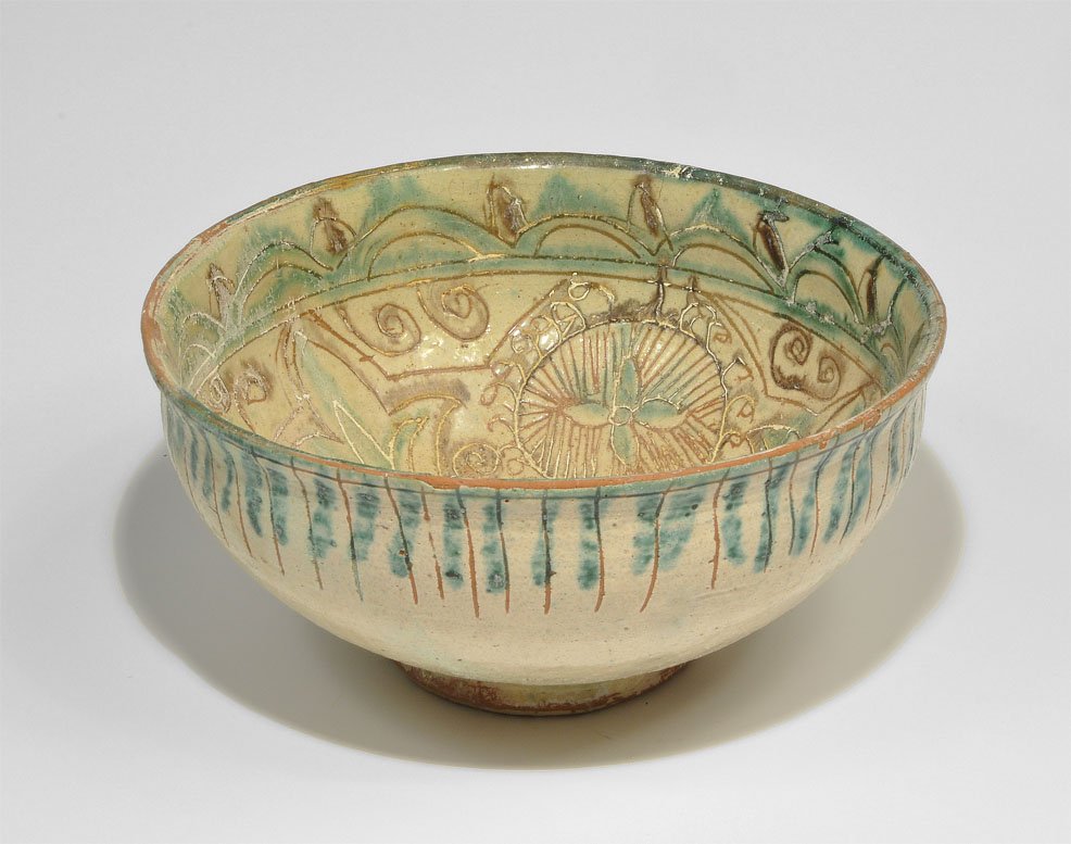 Islamic Bamiyan Style Green-Glazed Bowl: An undated decorative reproduction of a broad pedestal bowl in cream-glazed terracotta with decorative detailing; to the outer rim, a series of incised vertical lines revealing the underlying terracot