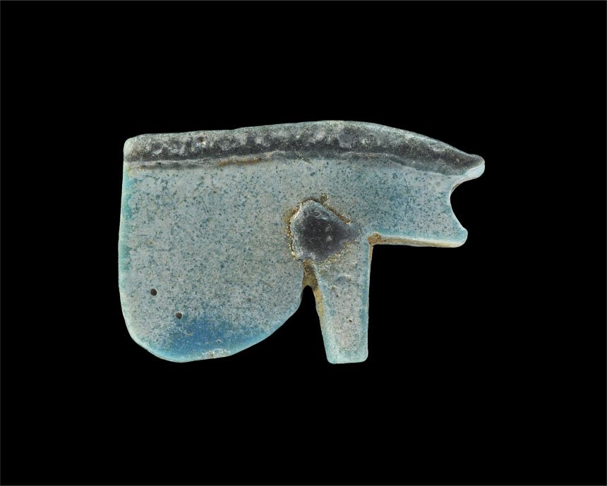 Egyptian Faience Wedjat Eye Amulet: Saite Period, circa 624-525 BC. A faience amulet in the form of the wedjat eye in blue with black brow and pupil, pierced for suspension. Property of a London Gentleman; acquired before 1985. 2.65 gra