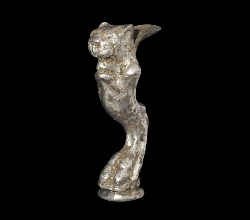 Roman Silver Zoomorphic Miniature Casket Leg: Circa 1st century AD. A cast silver miniature casket leg formed as a claw clutching a waisted disc finial, the leg extending to a feline head with open jaws and short supporting plate behind. Property