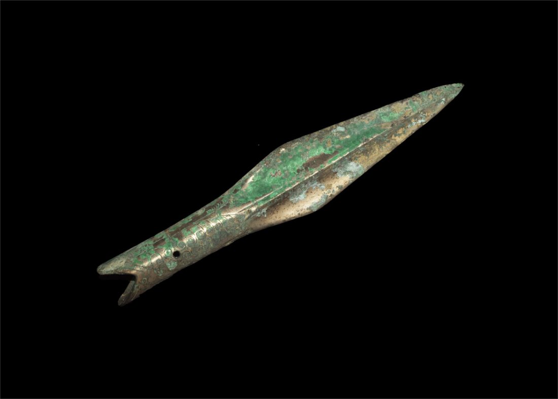 Chinese Bronze Socketted Spearhead: Han Dynasty, 206 BC-220 AD. A bronze spearhead with large engraved socket, split at the lower edged and pierced; the design a leaf-shaped panel with scrolled detailing. Property of a London Gentleman;