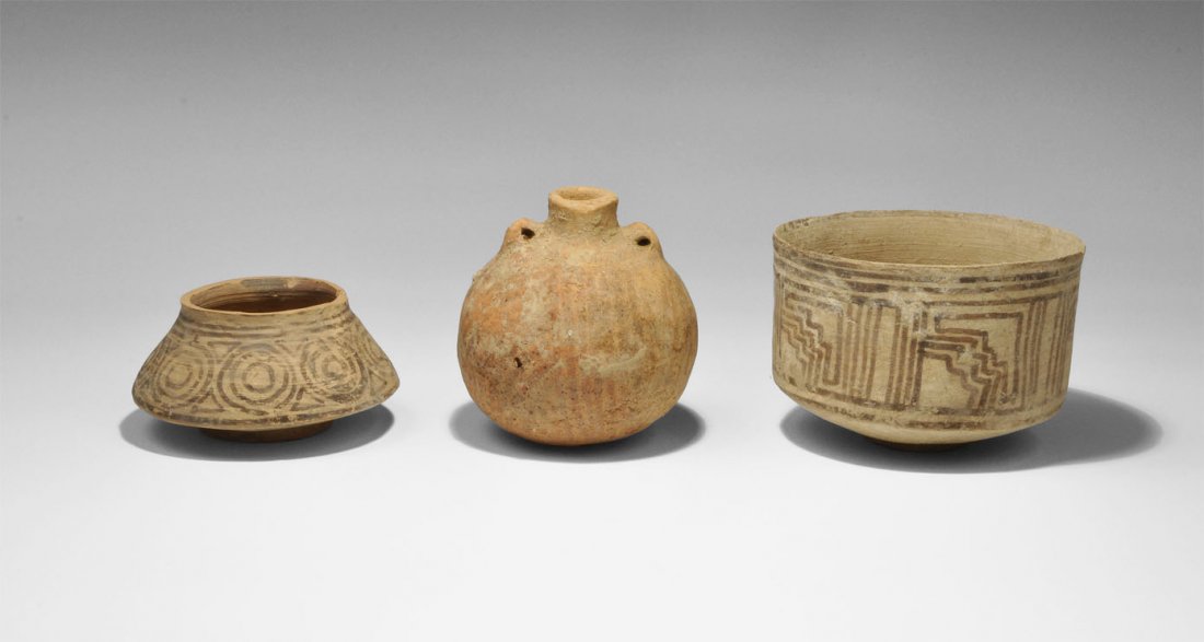 Indus Valley Ceramic Vessel Group: Circa 2nd millennnium BC. A mixed group of Indus Valley civilisation ceramic vessels comprising: a creamware pot with pedestal base, decorated with brown stepped geometric patterns; a low terracotta b