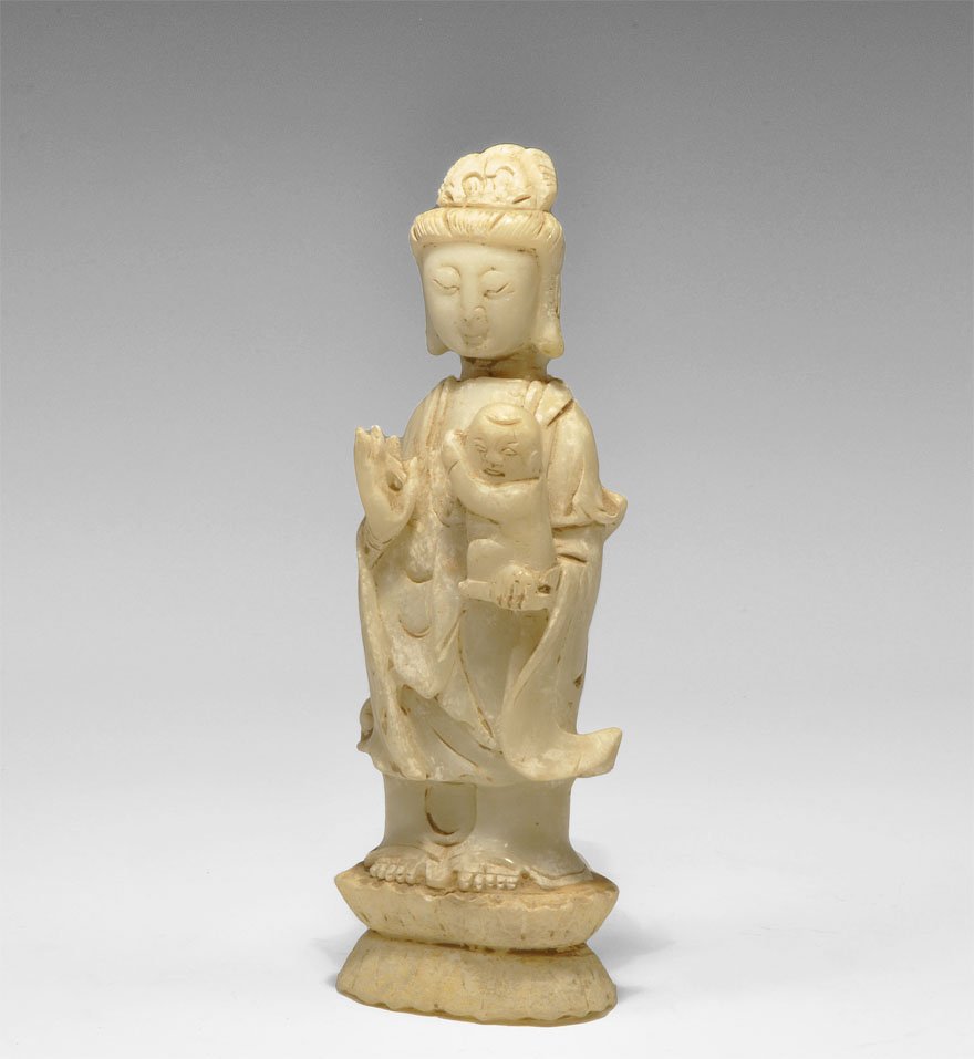 Chinese Alabaster Female Bodhisattva Figurine: Circa 19th century AD. A Chinese Buddhist alabaster figurine depicting a bodhisattva (possibly Guanyin, the bodhisattva of compassion) holding a child, standing on a pedestal in frontal pose wearing f