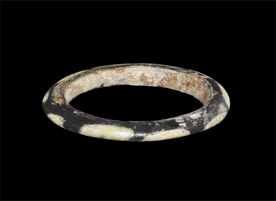 Islamic Glass Polychrome Bangle: An undated glass polychrome D-section bangle with iridescent surface, dark blue with yellow swirls. Property of a Middlesex Gentleman; acquired in the early 1980's. Glass, 30 grams, 74 mm (3").