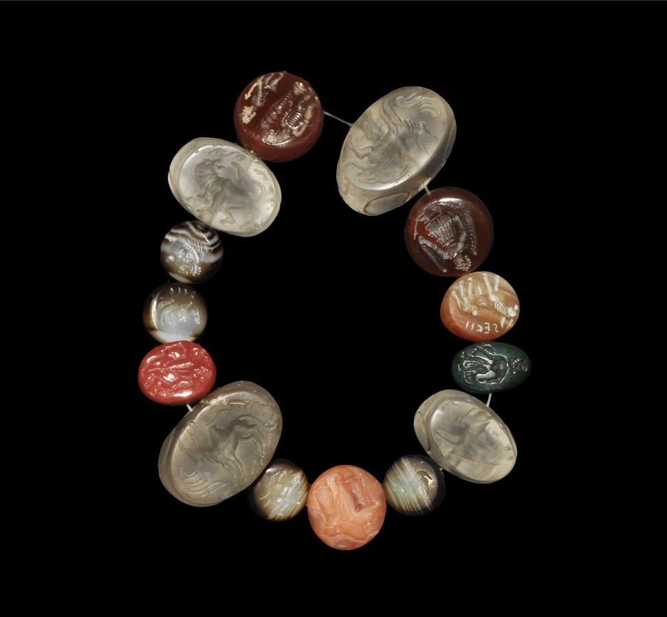 Near Eastern Crystal and Stone Seals Group: A mixed group of hardstone and crystal seals of various dates, pierced for suspension, comprising: four clear crystal seals, four small rouded banded agate seals, two carnelian seals, two orange agate