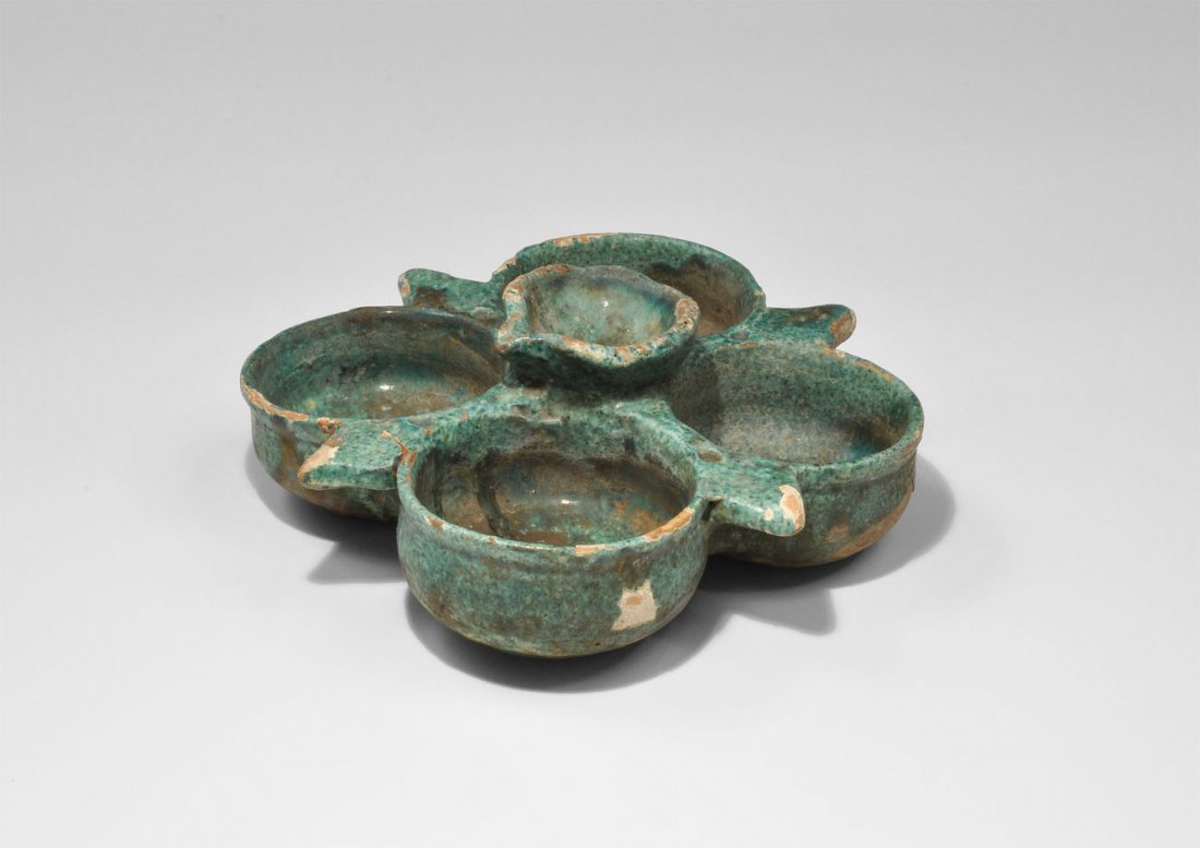 Islamic Glazed Spice Dish: Circa 18th century AD. A green-glazed spice tray comprising four dishes arranged in a quatrefoil pattern with rhomboid embellishments, around a raised smaller central dish with spout. UK private colle