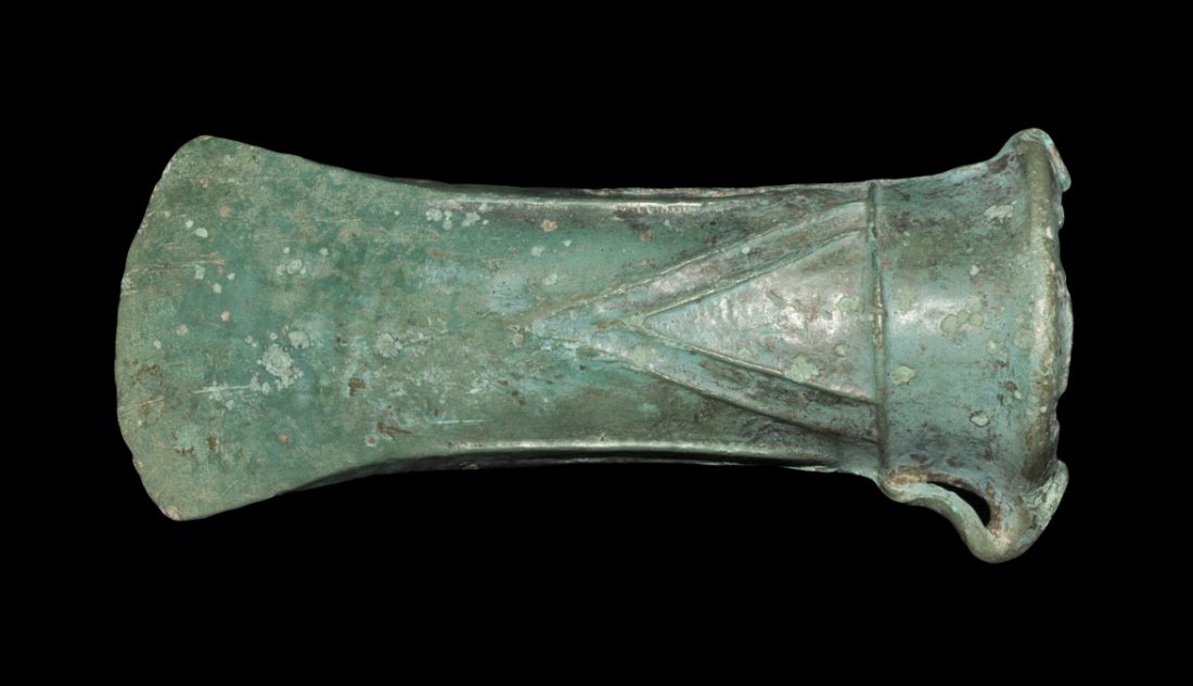 Bronze Age Bronze Looped and Socketted Axe Head: Middle European, circa 800-500 BC. A cast looped and socketted axe head with flared edge, collar to mouth and raised V-shaped rib to each face. Property of a European Gentleman living in the UK; ex pr