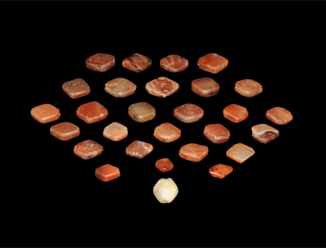 Near Eastern Group of Carnelian Beads: 1st millenium AD. A group of twenty-eight lozengiform beads, twenty-seven carnelian and one alabaster, assorted sizes. Ex Yagiello collection; acquired on the London and Paris art markets 1975-85. Sto