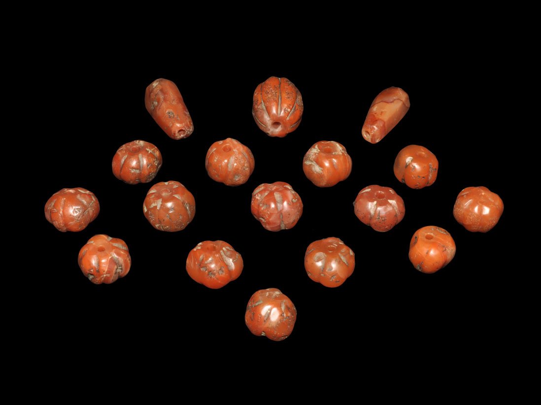 Near Eastern Group of Persian Red Agate Beads: 1st millennium BC and later. A group of seventeen 'melon' in red agate; fifteen 'melon' shaped, with one larger; two facetted cylinders; some probably reworked. Ex Yagiello collection; aquired on the