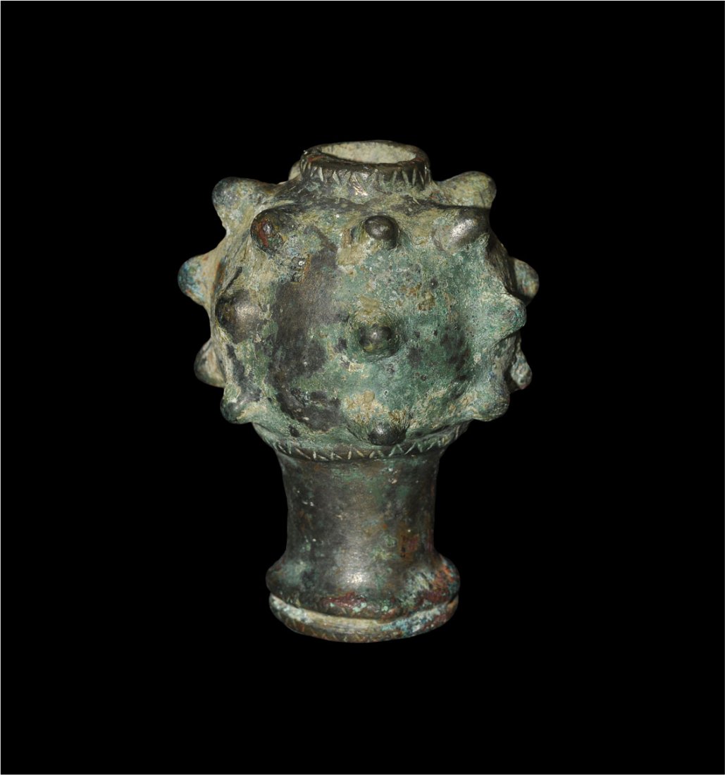Near Eastern Luristan Bronze Mace Head: Bronze Age, circa 1250-650 BC. A cast bronze mace head comprising a tubular socket and bulb; the socket with collar to the mouth, the bulb with regularly-placed short spikes and collars above and belo