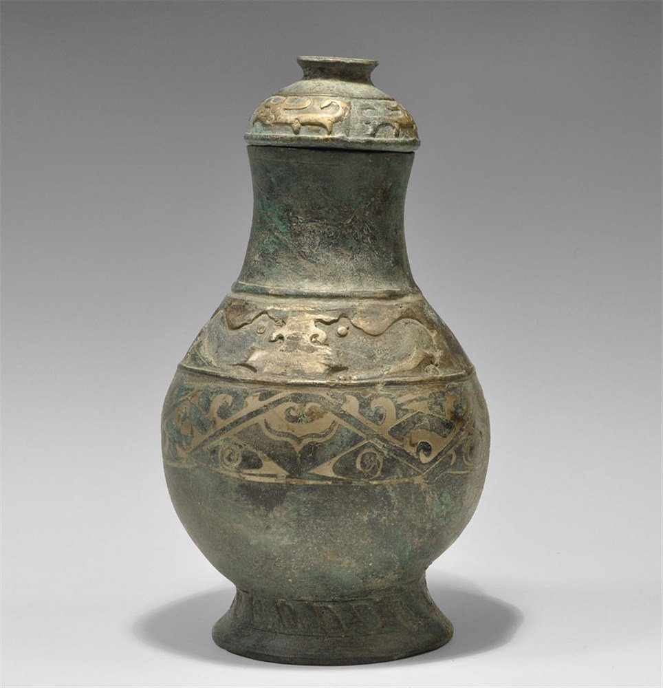 Chinese Han Dynasty Style Bronze Lidded Vessel: A large undated cast bronze vessel with conical base, globular nody and tall neck; to the base a slashed band, with gilt-bronze scrolled patterns to the body and shoulder; the lid a hemispherical cap 