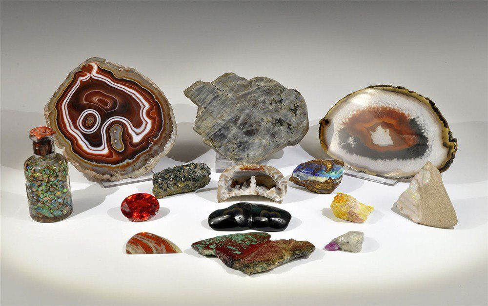 Collection of Mineral Specimens: A mixed group of fourteen mineral specimens comprising; 2 agate slices, 1 thick slice of labradorite, 1 bottle of opal chips in fluid, 1 polished obsidian, 1 ruby crystal in matrix, 1 small geode with