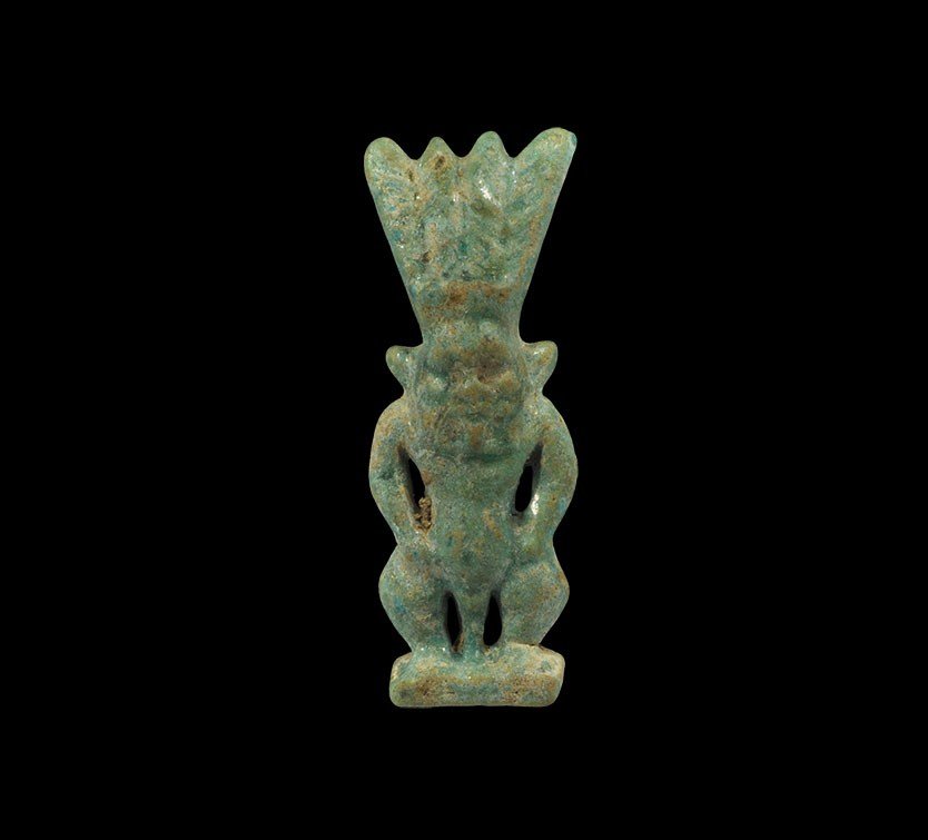 Egyptian Faience Turquoise-Glazed Bes Amulet: Third Intermediate Period, 1070-712 BC A turquoise-glazed composition amulet of the dwarf god Bes, depicted squatting, with short legs and rounded belly; to the head, a tall feathered crown; with inte
