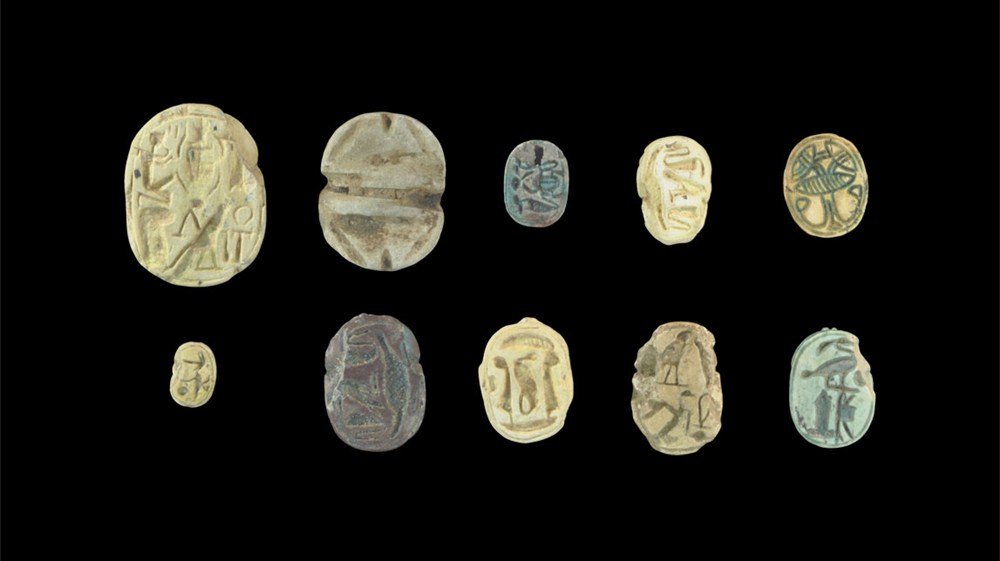 Egyptian Faience and Stone Scarab Group: New Kingdom-Ptolemaic Period, 1470-30 BC A mixed group of scarabs, one in dark stone, one in light stone, two blue-glazed faience, five in unglazed white ceramic, one stone scaraboid; designs and text