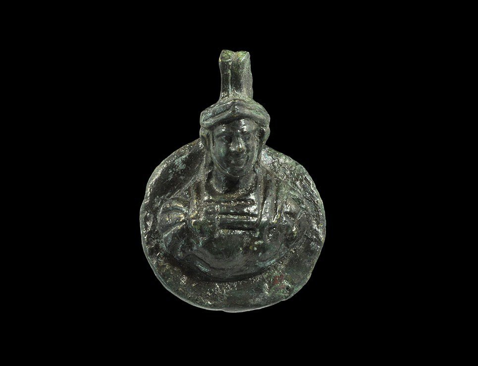Roman Bronze Military Phalera of a General: 1st-3rd century AD A cast phalera depicting a military bust modelled in the round; the youthful figure wearing a stylised helmet with crest and brow-band, armoured cuirass with pteruges to the shoulde