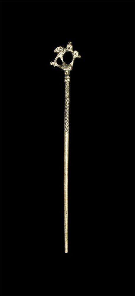 Islamic Silver Hair or Dress Pin: A dress pin with tapering shaft and openwork head; the shaft with rilled herringbone pattern to the upper third; the head formed as a sitting bird surmounted by a second bird with spread wings, both w