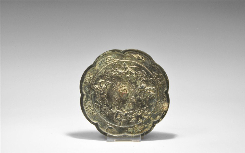 Chinese Bronze Mirror with Polo Player Motifs: Han Dynasty, 206 BC-220 AD A cast octofoil mirror with one polished surface; to the reverse a central pierced boss surrounded by images of horsemen playing polo amid vegetation; to the borders, a band