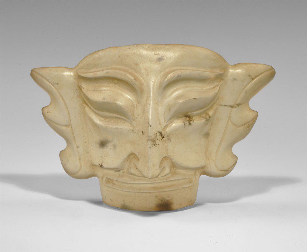 Chinese Tibetan Glass Grotesque Face Mask: Circa 20th century AD. A carved glass face mask in Art Deco style with grotesque features, trilobe flange ears and triangular nose. Acquired on the London art market in the 1960's. 795 grams, 19 cm (7
