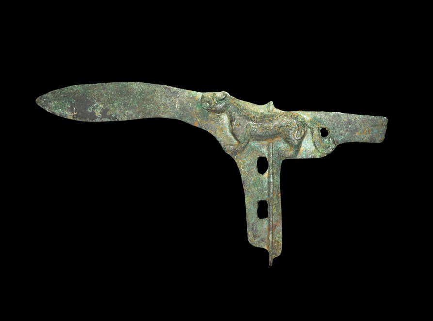 Chinese Zoomorphic Bronze Halberd: An undated archaistic Chinese style cast bronze halberd with leaf-shaped blade, transverse rib with attachment holes; the blade with running lion motif to the rear, modelled in low relief. Property of