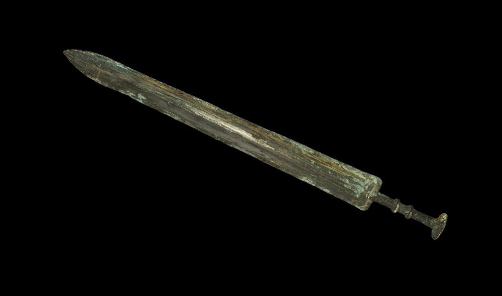 Chinese Han Dynasty Bronze Sword: Han Dynasty, 206 BC-220 AD. A cast bronze short sword with central midrib to the tapering blade; transverse discoid ribs to the grip and large discoid pommel above; the blade with engraved characters 