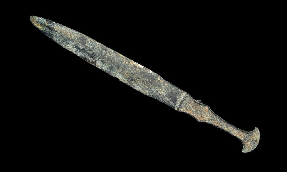 Near Eastern Luristan Short Sword: Bronze Age, 1200-800 BC. A cast bronze dagger comprising a flanged hilt and narrow blade with prominent central rib. UK art market, acquired prior to 1985. 242 grams, 33.5 cm (13 1/4"). [No Reserve]