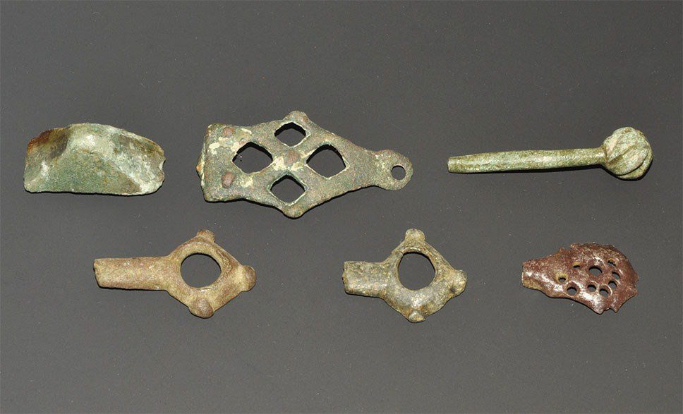 Viking Bronze Pommel and Artefact Group: 7th-10th century AD. A group of mixed Viking era bronze items comprising: a cast stirrup mount,a pierced mount, the upper section of a pin and two harness link terminals; with an Anglo-Saxon sword pom
