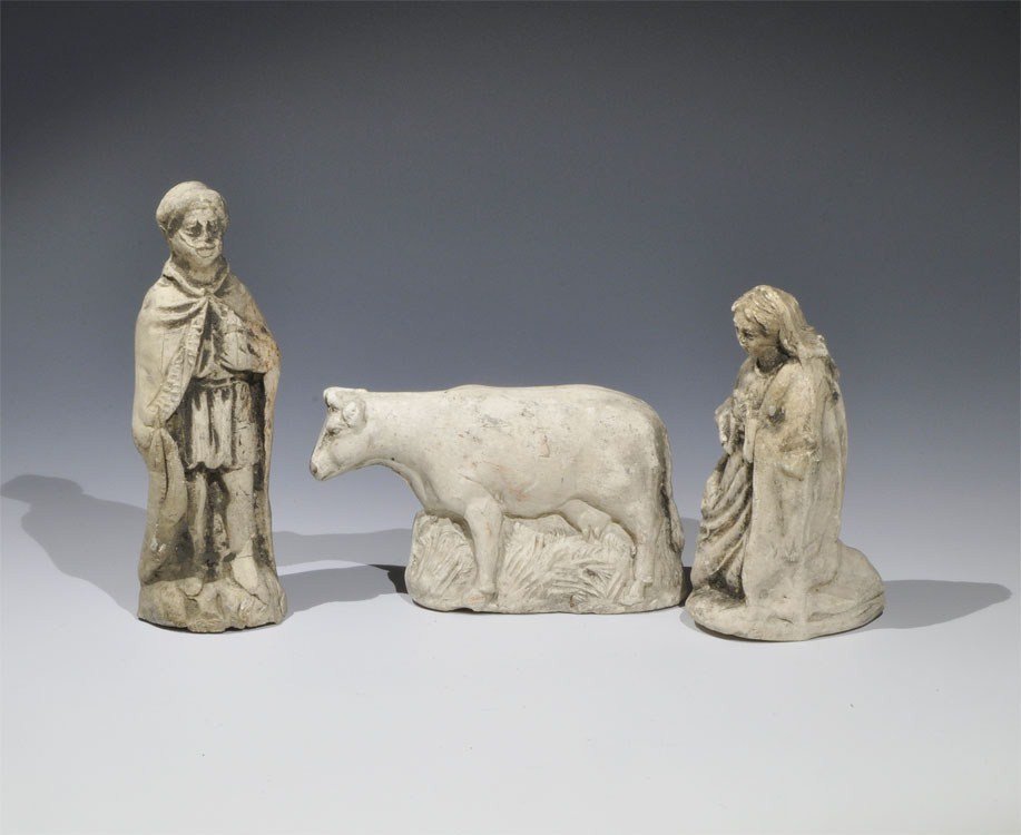 Post Medieval Pipe Clay Figurine Group: 18th century AD. A mixed group of cast figurines, hollow to the underside, comprising: one cow in long grass; one cloaked standing male figure with vessel clasped to the chest; one cloaked kneeling fe
