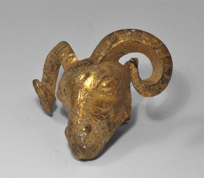 Chinese Han Dynasty Style Gilt-Bronze Ram's Head Mount: An undated hollow cast archaistic gilt bronze ram's head in 206 BC-220 AD style, with two attachment lugs to reverse. Acquired on the London art market in the 1960's. 63 grams, 60 mm (2 1/4").