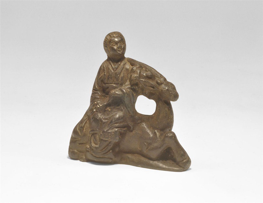 Chinese Yuan Bronze Stag and Male Figure: Yuan Dynasty, 1271-1368 AD or later. A cast bronze figurine depicting a robed male seated on a recumbent stag, his left hand placed on the stag's brow. Acquired on the London art market in the 1960's.