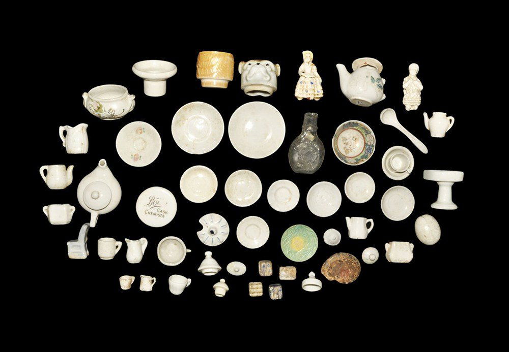 Post Medieval Victorian Dolls House Crockery Collection: 19th century AD. A mixed group of miniature ceramic plates, jugs and vessels, a ladle, dog-head jar lid, glass tablespoon measure, polychrome seated lady, pseudo-egg and miniature washstand and chair;