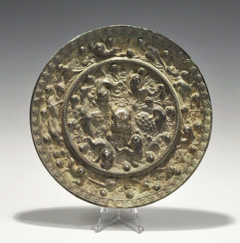 Chinese Han Dynasty Style Bronze Mirror: An undated archaistic cast disc mirror in Han Dynasty, 206 BC-220 AD style with one polished surface; to the reverse, a pierced central boss in the form of a quadruped surrounded by grapes, birds and 