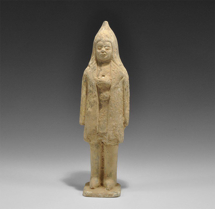 Chinese Ceramic Soldier Figurine: Northern Wei Dynasty, 386-534 AD A figurine with tall hood, long coat and high boots, standing on a square base; the hands raised to the chest, pierced; white pigment to the face and coat, black to th