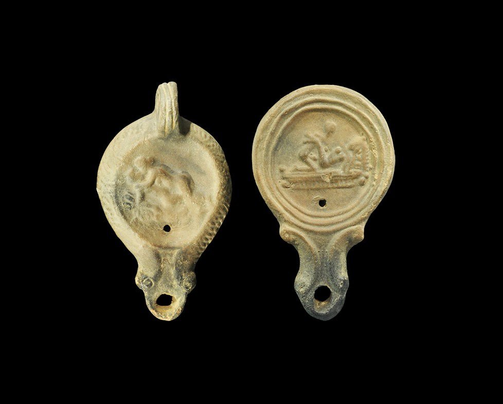 Roman Style Erotic Oil Lamp Group: A group of two undated archaistic ceramic oil lamps in 1st-2nd century AD style comprising: one with scrolled nozzle and pierced lug to the rear, depicting two lovers on a couch; one similar, no lug, 