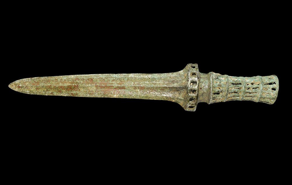 Chinese Style Bronze Dagger with Openwork Handle: An undated archaistic cast dagger with parallel-sided blade, openwork guard and hollow openwork grip; the blade with midrib and ribs to the edges; the guard with rectangular voids, waisted and the gri