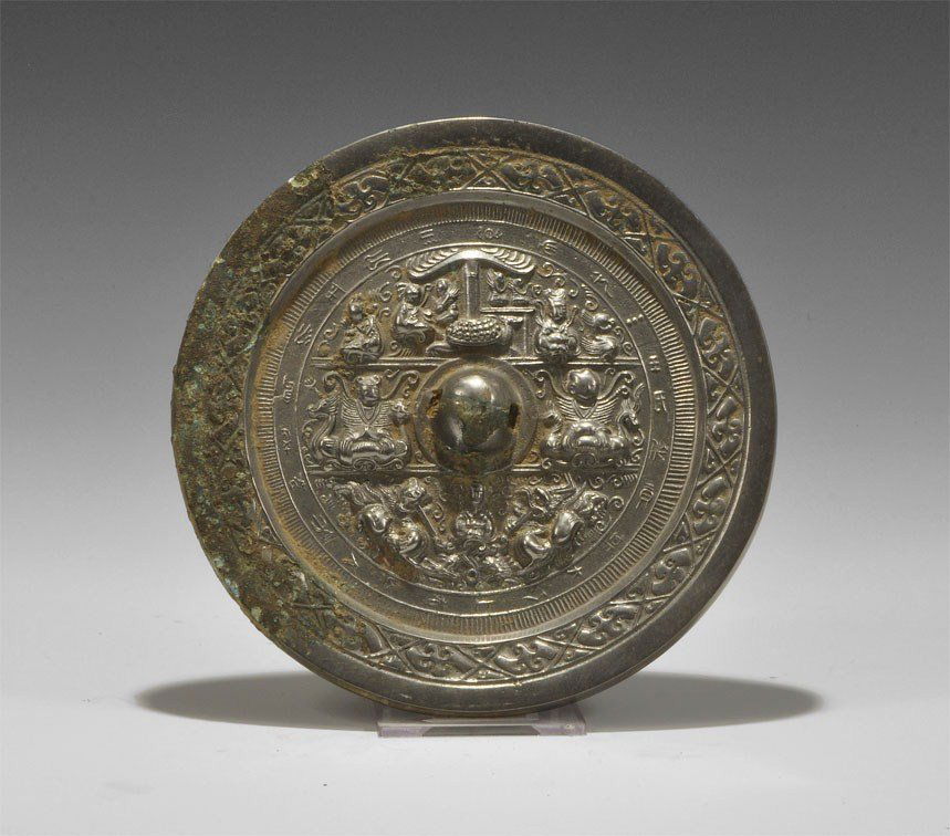 Chinese Style Tinned Bronze Epigraphic Mirror: An undated cast disc mirror; to the reverse, a central pierced lug with three tiers of animal and human motifs within panels surrounded by a band of text. 786 grams, 16.5 cm (6 1/2"). Property of a Lo