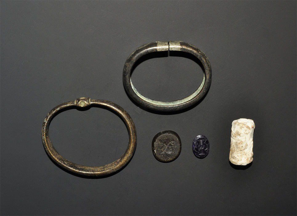 Near Eastern Mixed Artefact Group: 1st millennium BC and later. A mixed group of artefacts comprising: an ancient carved stone cylinder seal; an undated archaistic olive stone intaglio depicting janiform heads; an undated archaistic am