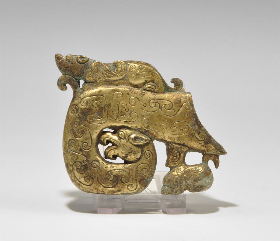 Chinese Gilt-Bronze Chou Style Dragon Sword Chape: An undated archaistic cast gilt bronze sword chape formed as a coiled dragon with scroll decoration to the flanks, its body supported on its own head and a small quadruped beneath; above, a stylised c