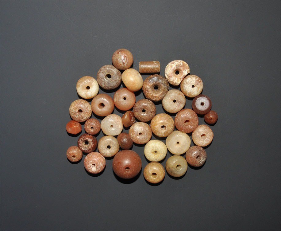 African Carnelian Tribal Bead Group: A mixed group of thirty four old undated carnelian and agate beads comprising: one tubular, three hexagonal-section and twenty-nine globular, with one globular opaque glass bead; Niger delta workmansh