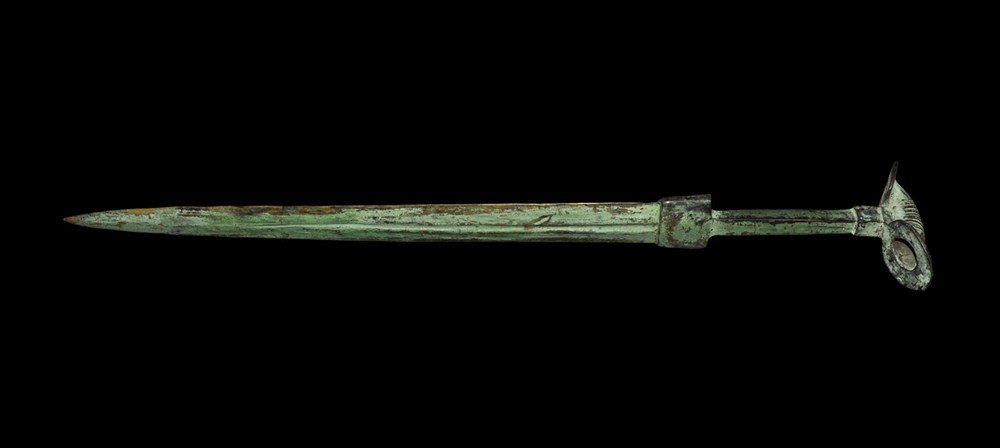 Bronze Age Luristan Style Bronze Sword: A very large and heavy undated cast bronze anchaistic sword with central channel, lanceolate blade, rectangular plate at the guard, square-section hilt and the pommel with transverse tubular profile a